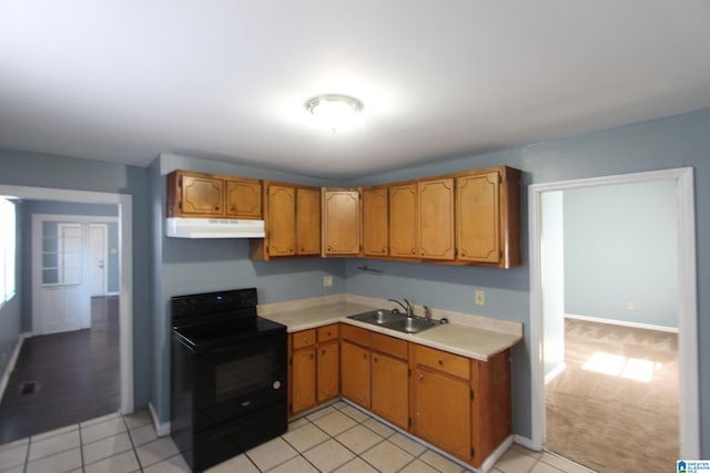 kitchen featuring black electric range, brown cabinets, light countertops, a sink, and under cabinet range hood