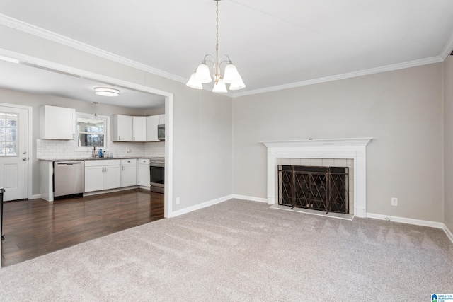 unfurnished living room with ornamental molding, a tile fireplace, a notable chandelier, and dark colored carpet