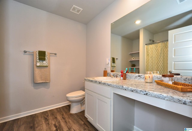 bathroom featuring baseboards, visible vents, toilet, wood finished floors, and vanity