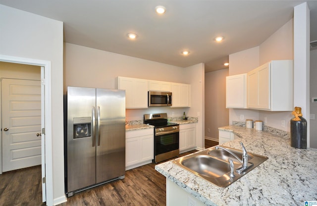 kitchen with dark wood-style floors, white cabinetry, stainless steel appliances, and a sink