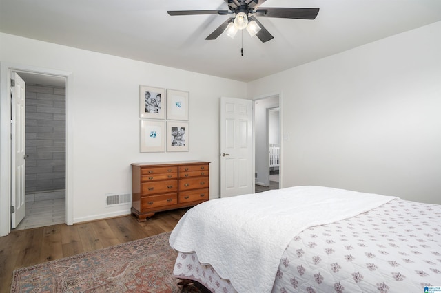 bedroom featuring baseboards, visible vents, a ceiling fan, ensuite bath, and wood finished floors