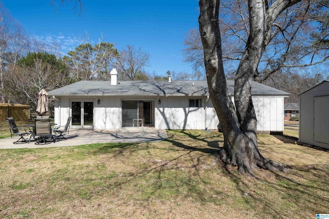 rear view of property with a patio, a chimney, a storage unit, a lawn, and an outdoor structure