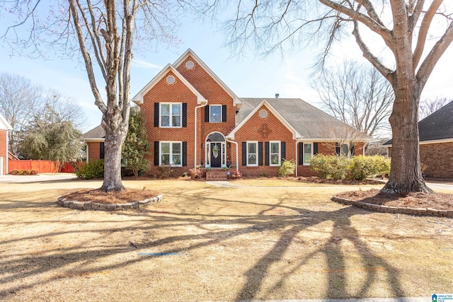 view of front facade with brick siding and fence