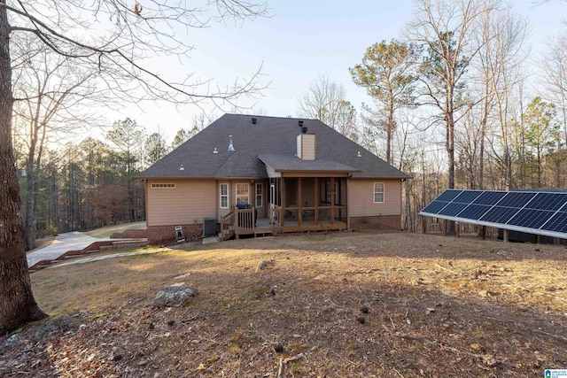 back of property with ground mounted solar panels, roof with shingles, and a chimney