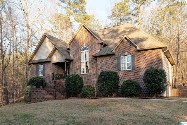 view of front facade featuring brick siding, a front yard, and roof with shingles