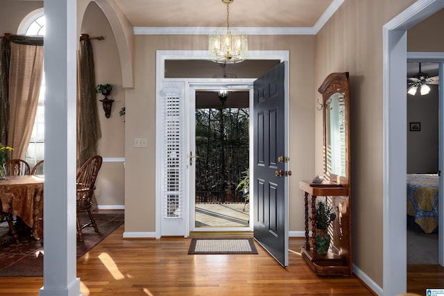 entrance foyer with crown molding, wood finished floors, baseboards, and a chandelier