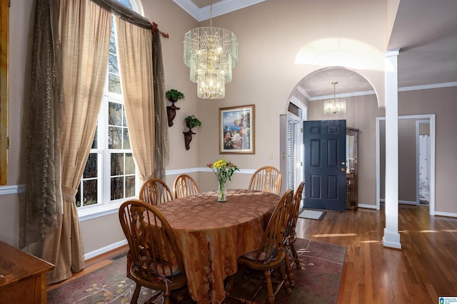 dining area with crown molding, baseboards, wood finished floors, arched walkways, and a notable chandelier