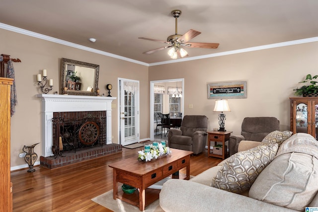 living area with crown molding, baseboards, ceiling fan, a fireplace, and wood finished floors