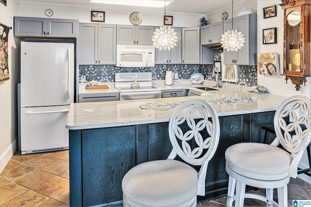 kitchen with white appliances, ornamental molding, a peninsula, gray cabinets, and a sink