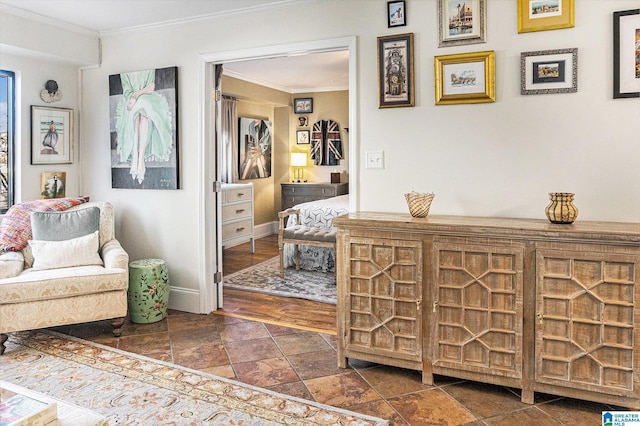 sitting room featuring stone finish flooring, ornamental molding, and baseboards