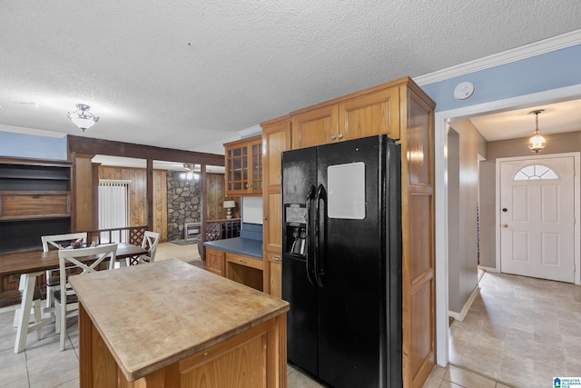 kitchen featuring glass insert cabinets, ornamental molding, a center island, black refrigerator with ice dispenser, and a textured ceiling