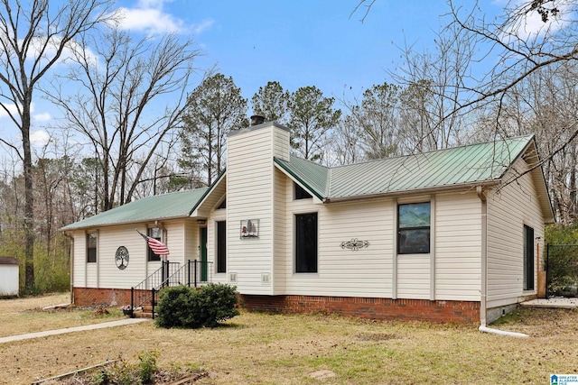 view of front of home featuring metal roof, a front lawn, and a chimney