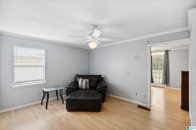 sitting room with light wood finished floors, a textured ceiling, and crown molding