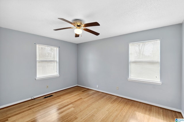 unfurnished room featuring a textured ceiling, baseboards, and hardwood / wood-style floors