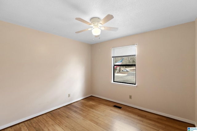 unfurnished room featuring a ceiling fan, visible vents, baseboards, and wood finished floors