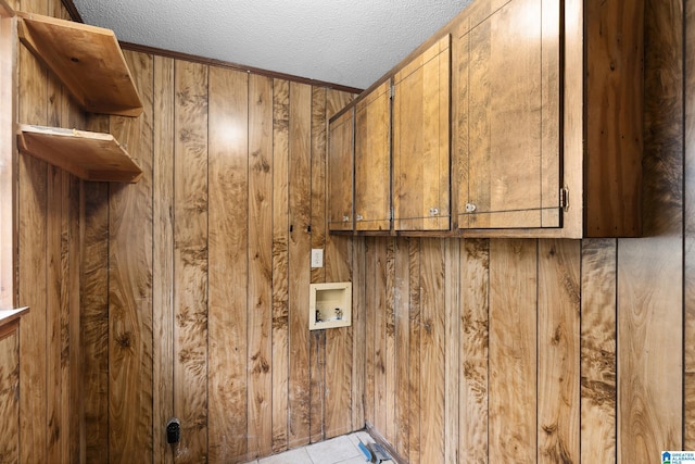 laundry area featuring cabinet space, wooden walls, washer hookup, and a textured ceiling