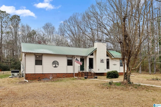 view of front of house with a front yard, metal roof, and a chimney