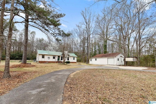 single story home featuring a detached garage, an outdoor structure, driveway, and a front lawn