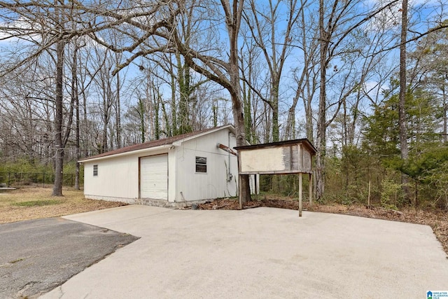 view of side of property with driveway, a detached garage, and an outdoor structure