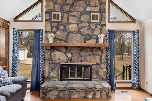 living room with lofted ceiling, a fireplace, wood finished floors, and visible vents