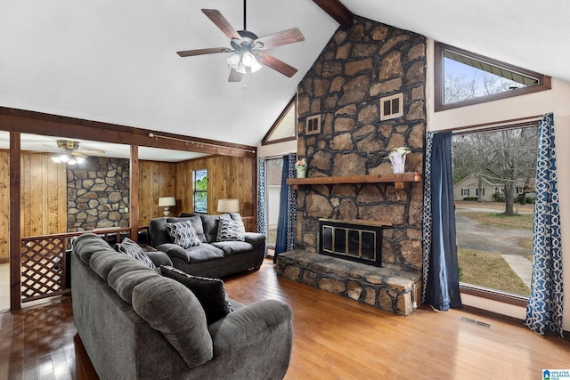 living area with a fireplace, visible vents, beamed ceiling, and wood finished floors