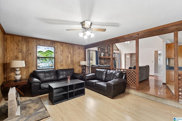 living area featuring light wood-type flooring, vaulted ceiling, ceiling fan, and a textured ceiling