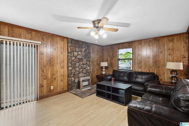 living room with heating unit, light wood-style floors, a textured ceiling, and wood walls