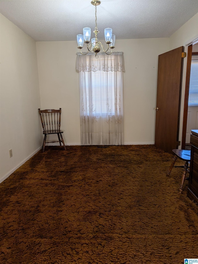 unfurnished room with carpet floors, a textured ceiling, baseboards, and an inviting chandelier