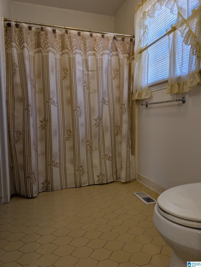 full bath with visible vents, toilet, and tile patterned floors