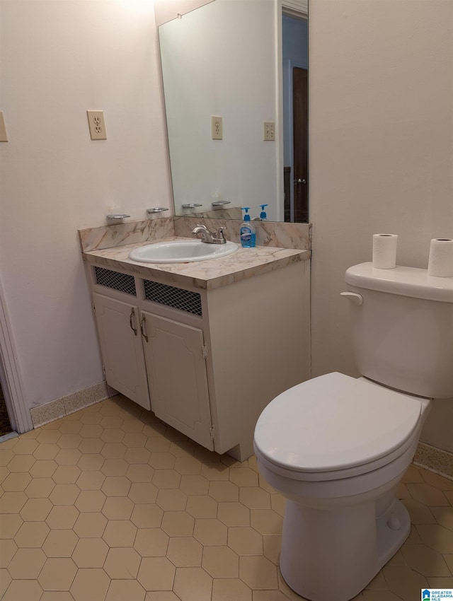 bathroom with tile patterned flooring, vanity, toilet, and baseboards