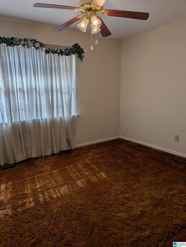 carpeted empty room featuring visible vents, baseboards, and ceiling fan