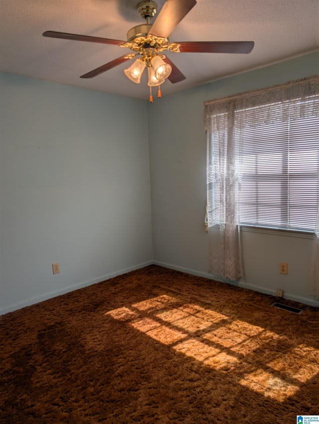 carpeted empty room with a ceiling fan, visible vents, and baseboards