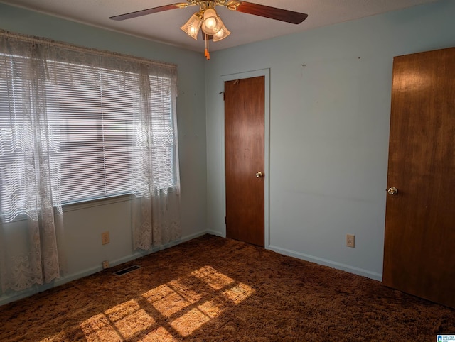 unfurnished room featuring baseboards, carpet, visible vents, and a ceiling fan