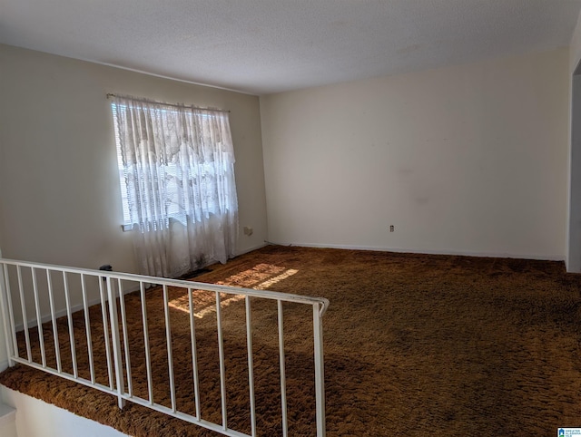 carpeted empty room with a textured ceiling