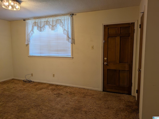 carpeted foyer featuring baseboards and a textured ceiling