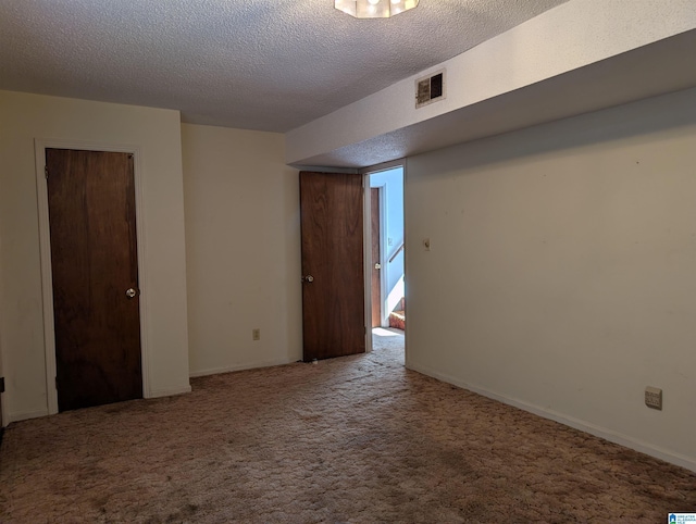 spare room with a textured ceiling, carpet flooring, and visible vents