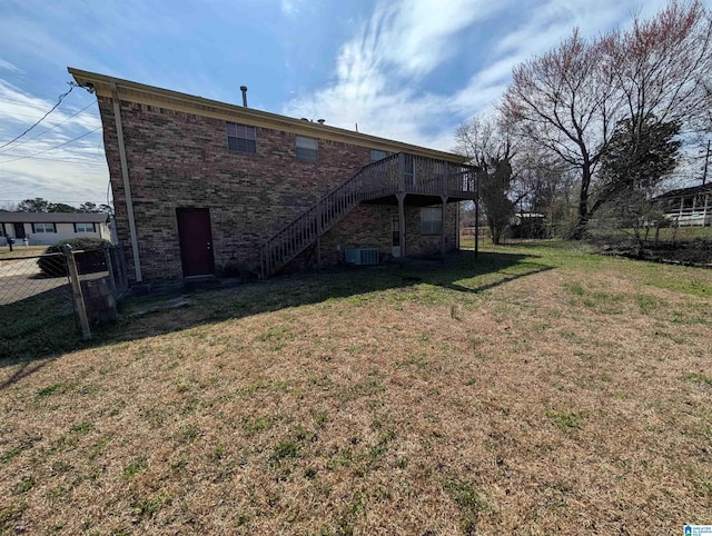 back of property with brick siding, a lawn, stairway, fence, and a wooden deck