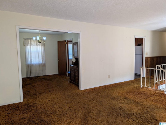 spare room featuring a textured ceiling, a chandelier, and carpet flooring