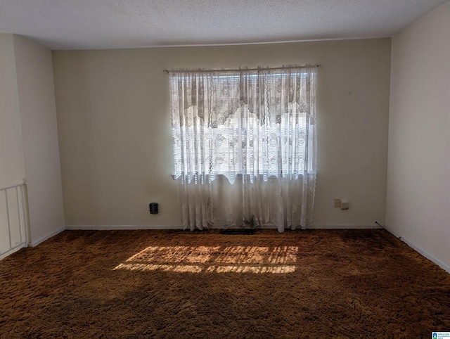 unfurnished room with carpet, baseboards, and a textured ceiling