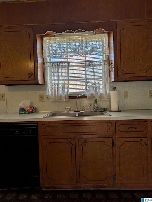 kitchen featuring black dishwasher, light countertops, a sink, and brown cabinets