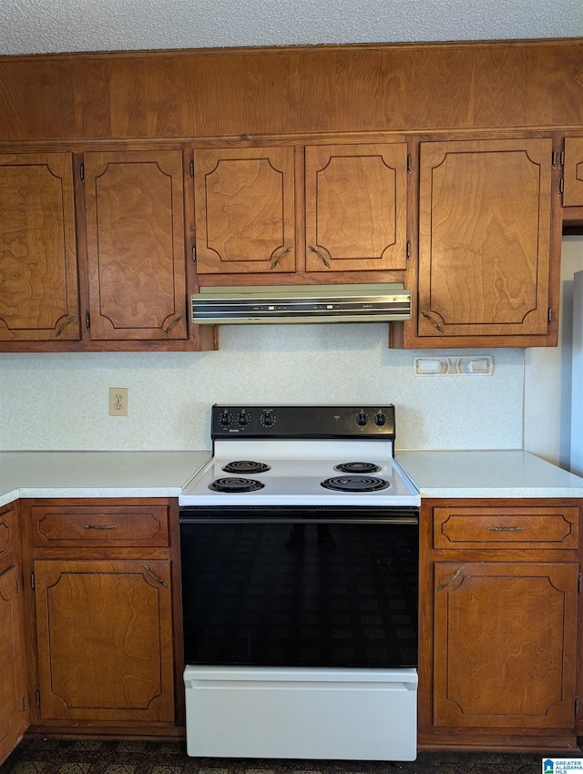 kitchen with electric stove, brown cabinets, light countertops, and under cabinet range hood