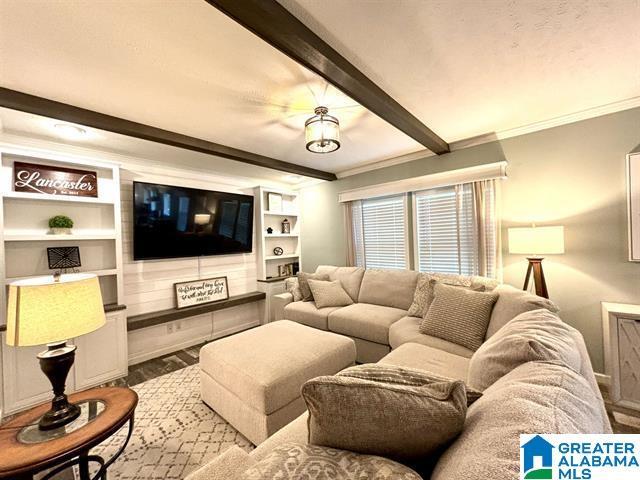 living room featuring ornamental molding, beam ceiling, and wood finished floors