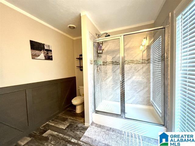 full bath featuring toilet, a shower stall, and wood finished floors