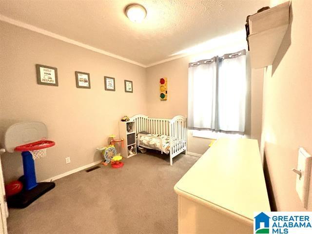 bedroom with carpet, visible vents, baseboards, and a textured ceiling