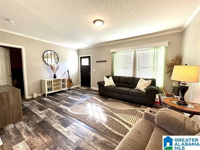 living area with ornamental molding, a textured ceiling, baseboards, and wood finished floors