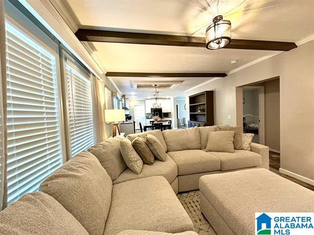 living room with baseboards, ornamental molding, and beamed ceiling