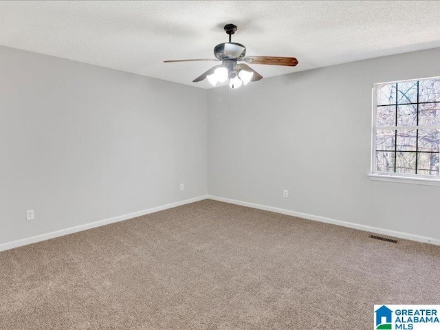 carpeted empty room featuring baseboards, visible vents, ceiling fan, and a textured ceiling