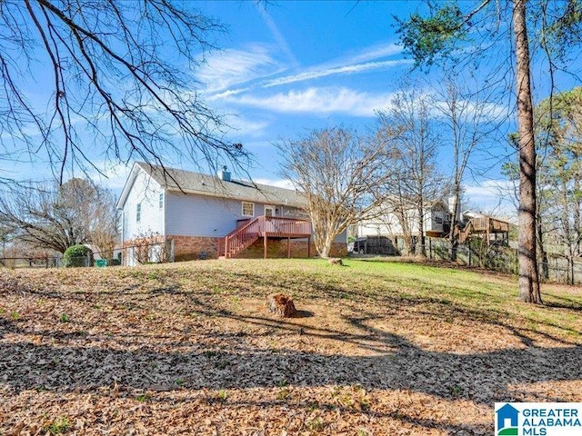 view of yard with fence, a wooden deck, and stairs