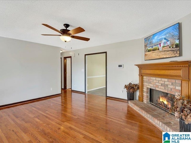 unfurnished living room featuring light wood-style floors, a brick fireplace, and baseboards