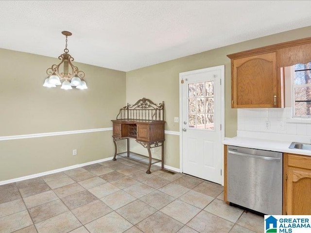 kitchen with baseboards, light countertops, stainless steel dishwasher, backsplash, and pendant lighting